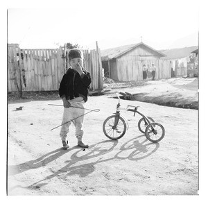 Young boy standing beside tricycle, Korea