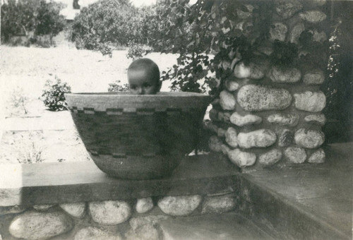 C.O. Barker Jr. sitting in a Native American-made basket on the porch of the C. O. Barker house in Banning, California