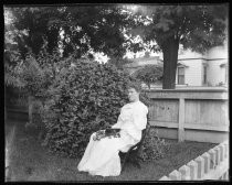 Woman in white dress, seated outdoors