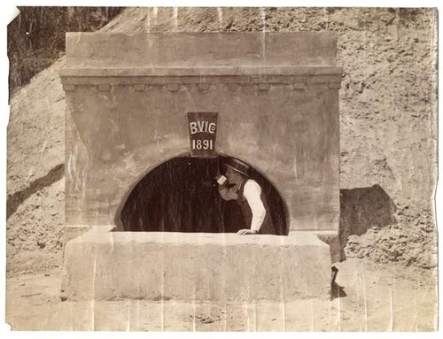 Man standing at entrance to Bear Valley irrigation system tunnel no. 1