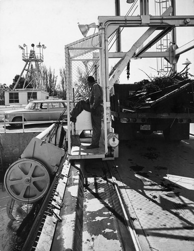 35 This is the opposite view of the trash rake showing the control man and the waiting dump truck. The trash will be collected and dumped by the trash rake. Note the rails upon which the rake structure is able to move horizontally across the intake canal