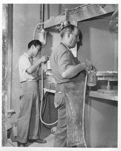 Larry Ogino (left), formerly a student of commercial art at San Jose State College in California, now relocated from the Poston Center and working for the Florence Art Company where he decorates figurines and giftware.--Photographer: Parker, Tom--Chicago, Illinois. 8/?/43