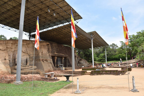 View of Gal Vihāra complex: four large Buddha statues: seated, standing and recumbent: "Buddhist" flag