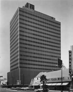 Photo of Lee Tower on Wilshire Boulevard, as well as a couple of food markets and Brown's Wilshire Bakery, facing west down Wilshire Boulevard