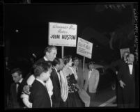 Supporters of the Un-American Activities Committee picketing director John Huston as he arrives at "Moulin Rouge" premiere in Los Angeles, Calif., 1952