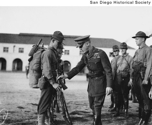 Marine General Smedley Butler inspecting a marine recruit's rifle at the Marine Corps Recruit Depot