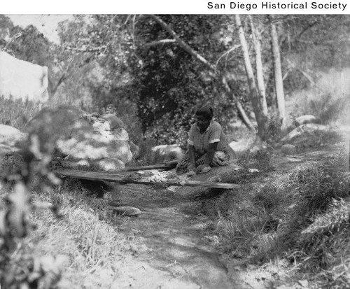 Indian woman washing clothes on a rock at Warner Hot Springs — Calisphere