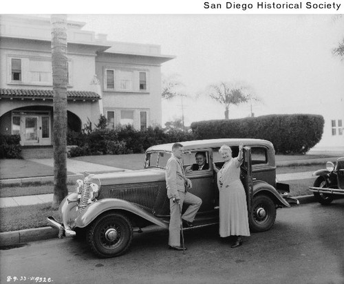 Ernestine Schumann-Heink and two men standing around an automobile parked in front of a house