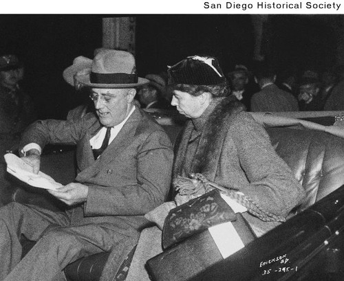 Franklin D. and Eleanor Roosevelt sitting in a car and looking at a piece of paper in Balboa Stadium