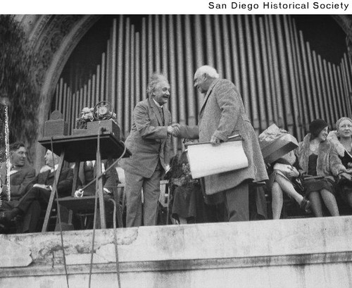 Albert Einstein shaking hands with another man at the Spreckels Organ Pavilion