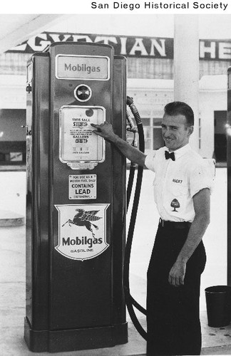 A gas station attendant standing next to a gas pump