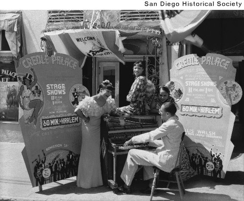 A man playing a piano with three women singing outside the Creole Palace