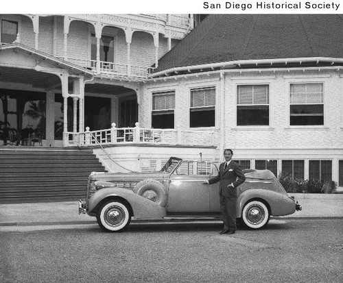 A man standing in front of a Buick automobile parked at the Hotel del Coronado