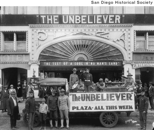 Soldiers and Marines on and near a truck parked in front of the Plaza Theater in downtown San Diego