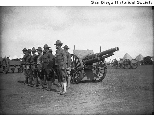 Soldiers at Camp Kearny standing at attention next to a field cannon