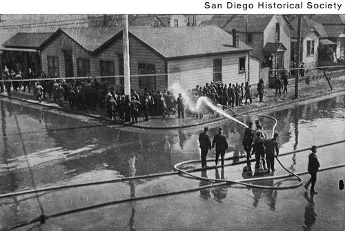 Police using a fire hose to quell the I.W.W. riot in downtown San Diego