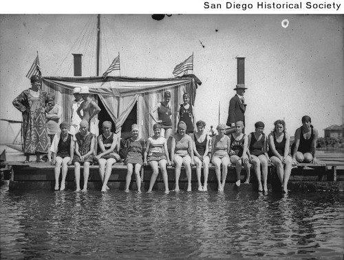 A group of women in bathing suits sitting on a low pier at Coronado's Tent City