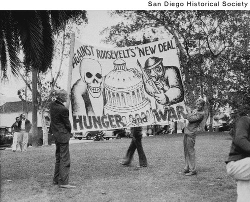 Two men holding an anti-New Deal sign at a Communist demonstration in New Town Park prior to the start of the riot