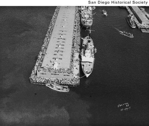 Aerial view of a large group of people on a pier docked with two ships