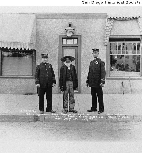 Two San Diego Police officers and a elderly Mexican man standing at the entrance to the police station