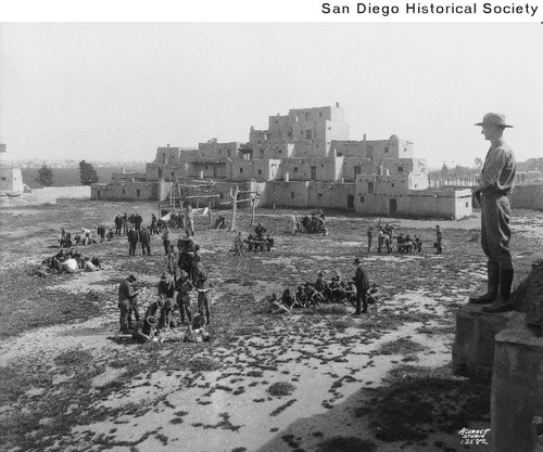 An adult leader overlooking several groups of scouts at the Indian Village