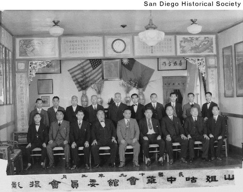 Group of men seated indoors beneath US and Chinese (now Taiwan) flags, possibly in the Benevolent Association Building