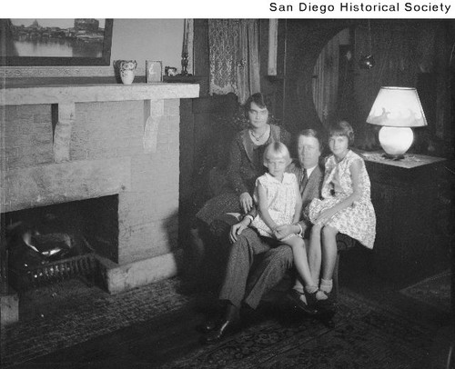 Donald Hanson with his wife and two daughters posed next to a fireplace