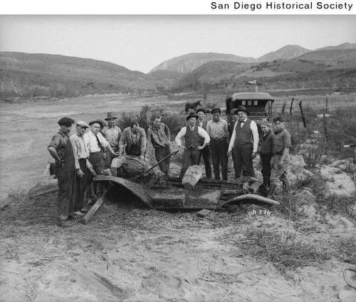 Group of men standing around a Ford automobile that had been buried in a flood