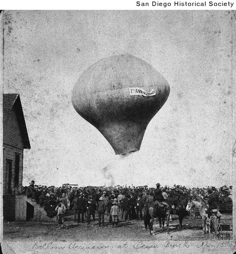 An early hot air balloon rises over a crowd during the first anniversary of Ocean Beach