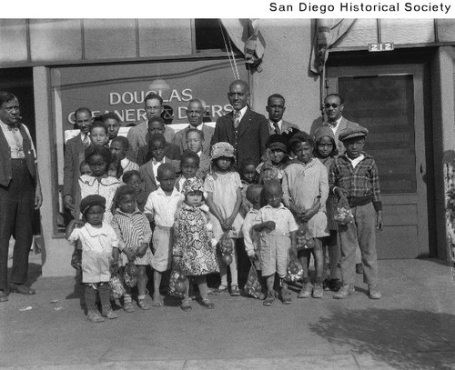 George Ramsey and a group of children and adults standing in front of Douglas Cleaners & Dyers