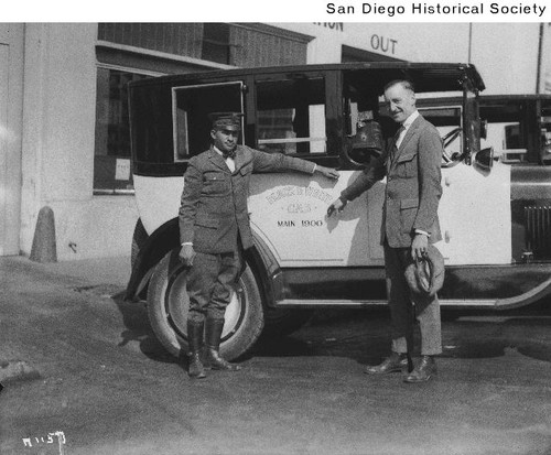 Two men standing in front of a Ralph Hamlin Cab Company cab