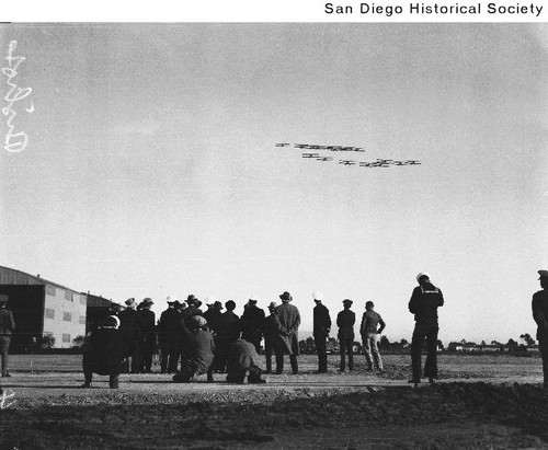 Group of people watching biplanes flying overhead