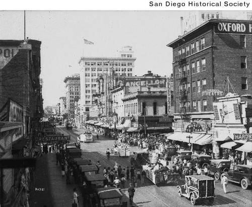 Street view of a parade from Fifth Avenue and F Street looking north