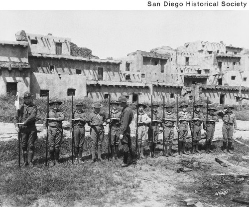 Group of Boy Scouts standing in a row in front of the Indian Village in Balboa Park
