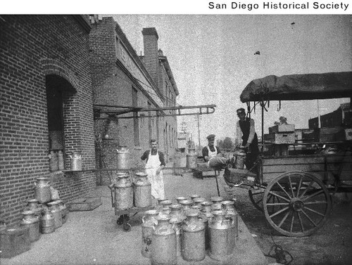Milk cans being unloaded from a delivery cart at the Bay City Market