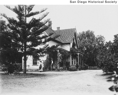 Man, woman, and girl standing in front of the Prentice Ranch house in Spring Valley