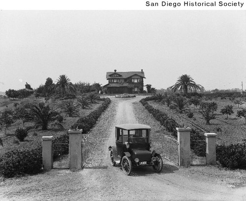 A man driving an automobile through the gate of the Holland residence