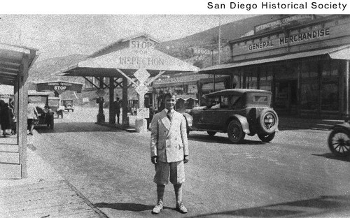 A well dressed young man standing at the U.S. Customs inspection station at the border