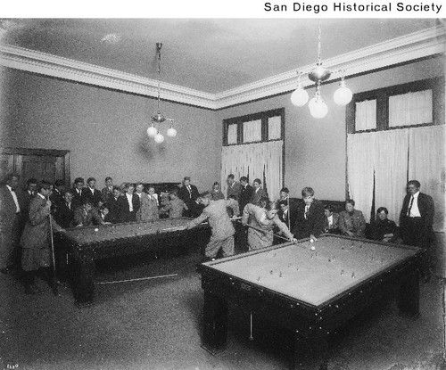 Group of men gathered around two snooker tables at the Young Men's Christian Association