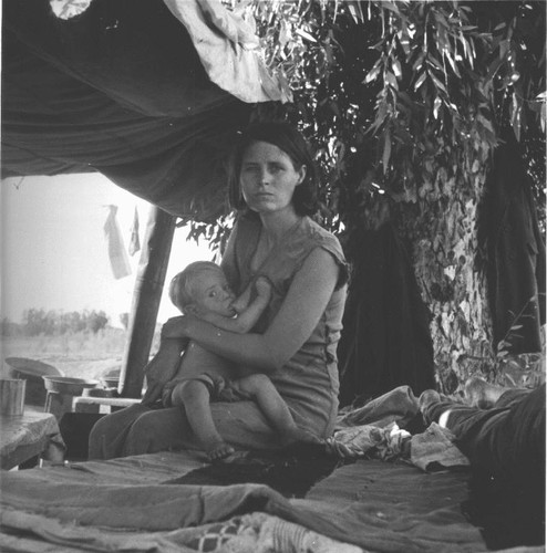 Drought refugees from Oklahoma camping, mother feeding child, August, 1936