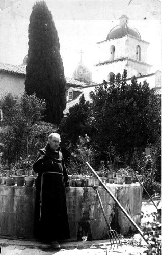 Padre in mission garden (possibly Mission Santa Barbara)