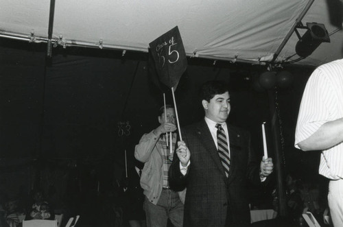 A man representing the Class of 55 carrying a candle