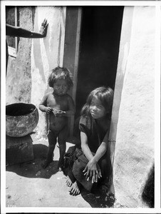 Two Hopi Indian children in the doorway of a native adobe dwelling, ca.1900