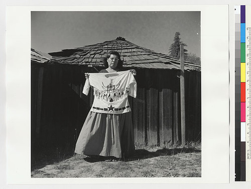 Essie Parrish holding costume; white decorated shirt, front, with black star design and abalone pendants