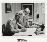Adrian Wilson and Ansel Adams [conversing at desk]