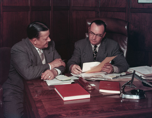 [Edmund G. Brown looking through papers with an unidentified man.]