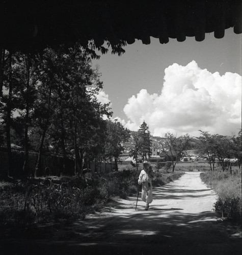Man walking down a road viewed from under an overhang