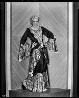 Peggy Hamilton modeling an evening gown with bell sleeves and a peplum, 1931