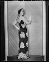 Peggy Hamilton modeling a black satin dinner dress with a floral design, 1931