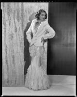 Actress Loretta Young modeling a white ermine spring jacket over a pale pink ruffled net gown, 1931